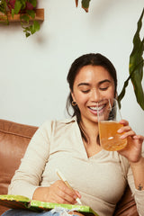 Modern Dose customer drinking Cognition Boost in passion fruit and writing in a notebook - moderndose.com